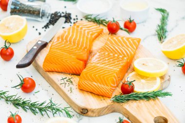 Limon domates ve diğer madde - sağlıklı gıda tarzı ahşap kesme tahtası üzerinde ham ve taze somon eti fileto