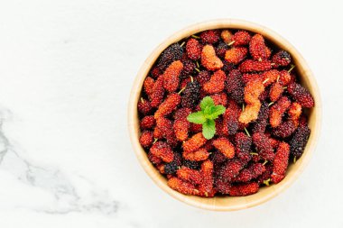 Kırmızı ve siyah dut meyve kase beyaz taş zemin üzerine