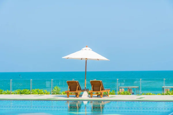 Belo guarda-chuva e cadeira em torno da piscina no hotel e r — Fotografia de Stock