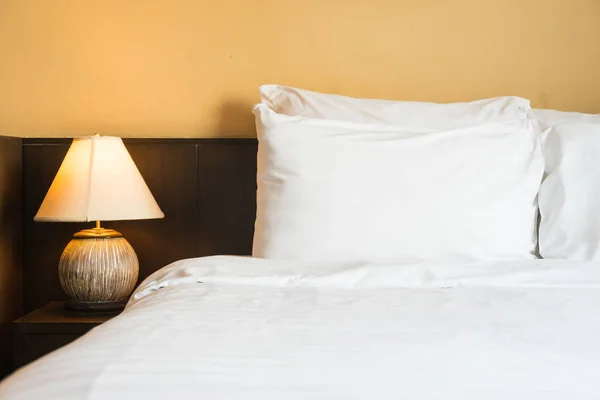 White comfortable pillow on bed with light lamp — Stock Photo, Image