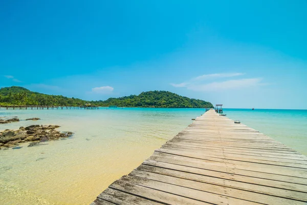 Träbrygga eller bridge med tropiska stranden och havet i paradiset är — Stockfoto