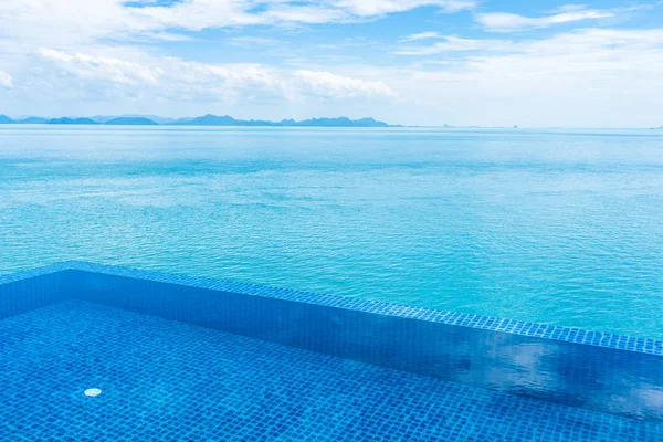 Beautiful outdoor swimming pool with sea ocean on white cloud bl — Stock Photo, Image