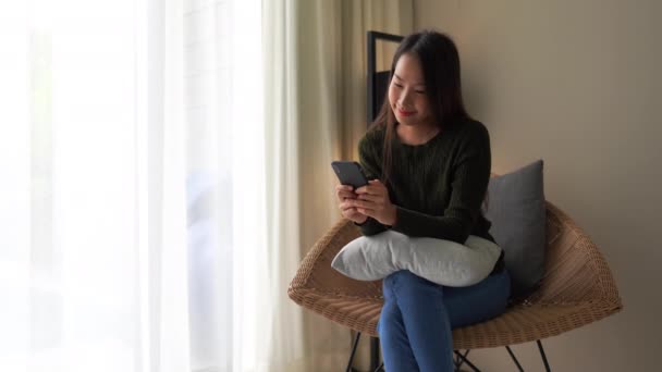 自宅でスマートフォンを使って美しいアジア系女性の映像を — ストック動画