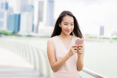 Asyalı kadın konuşmak veya metin için akıllı telefon veya cep telefonu kullanarak