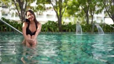 Güzel Asyalı bir kadının oteldeki havuzda dinlenirken çekilmiş görüntüleri.