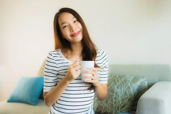 Retrato hermosa joven asiática mujer en sofá con taza de café —  Fotos de Stock