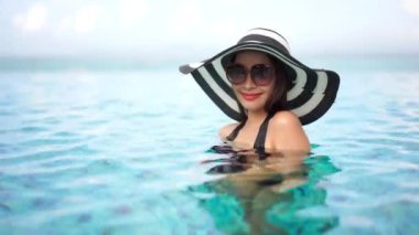 Güzel Asyalı bir kadının oteldeki havuzda dinlenirken çekilmiş görüntüleri.