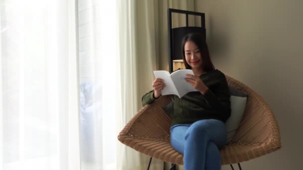 Видео Красивой Азиатской Женщины Читающей Книгу Диване Дома — стоковое видео