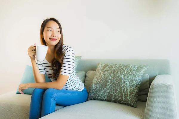 Retrato hermosa joven asiática mujer en sofá con taza de café — Foto de Stock