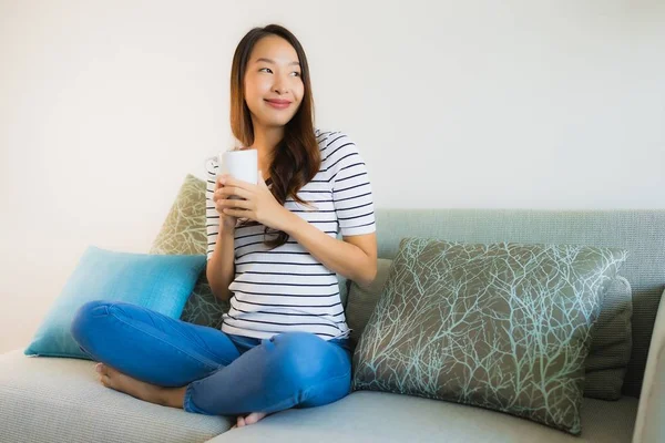 Retrato hermosa joven asiática mujer en sofá con taza de café —  Fotos de Stock