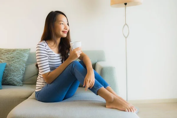 Retrato hermosa joven asiática mujer en sofá con taza de café —  Fotos de Stock