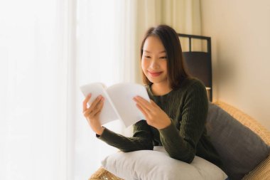 Asyalı güzel bir kadının kitap okuyup üzerine oturduğu portre.