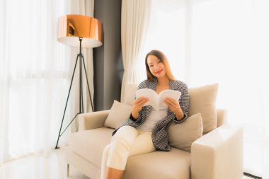 Asyalı güzel bir kadının kitap okuyup üzerine oturduğu portre.