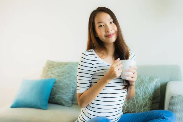 Retrato hermosa joven asiática mujer en sofá con taza de café —  Fotos de Stock