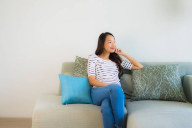 Güzel bir Asyalı kadın portresi. Kanepede mutlu bir gülümseme.