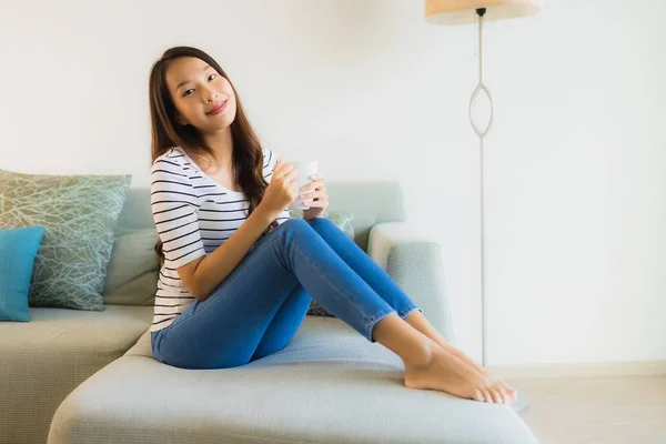 Retrato hermosa joven asiática mujer en sofá con taza de café —  Fotos de Stock