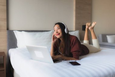 Bilgisayar ve kulaklık kullanan güzel Asyalı kadınların portresi.