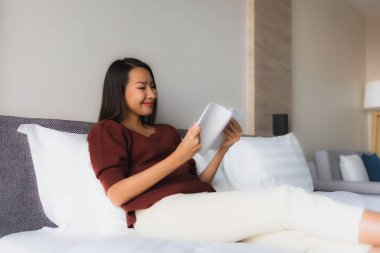 Yatakta kitap okuyan güzel Asyalı kadınların portresi.