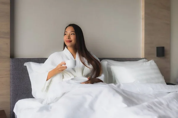 Porträt schöne junge asiatische Frauen mit Kaffeetasse auf dem Bett — Stockfoto