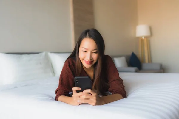 Portré gyönyörű fiatal ázsiai nők mobiltelefon az ágyban — Stock Fotó