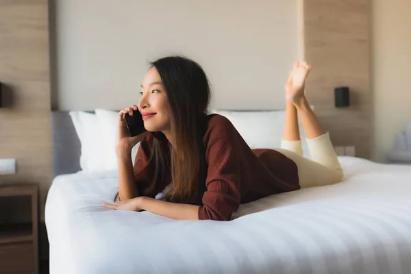 Porträt schöne junge asiatische Frauen mit Handy auf dem Bett — Stockfoto