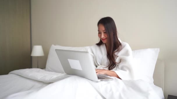 Beeldmateriaal Van Mooie Aziatische Vrouw Badjas Werken Met Laptop Bed — Stockvideo