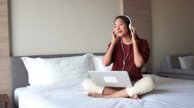 Asyalı kadının dizüstü bilgisayarla çalıştığı ve evde müzik dinlediği görüntüler.