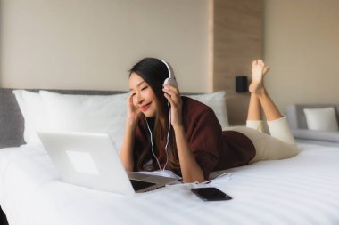 Bilgisayar ve kulaklık kullanan güzel Asyalı kadınların portresi.