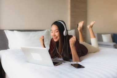 Bilgisayar ve kulaklık kullanan güzel Asyalı kadınların portresi.