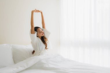 Portre güzel genç Asyalı kadınlar yatakta mutlu gülümsüyor.