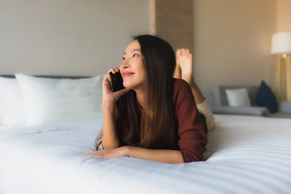 Porträt schöne junge asiatische Frauen mit Handy auf dem Bett — Stockfoto