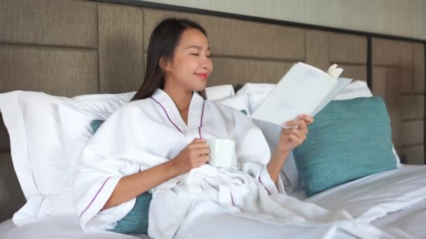 美しいアジアの女性が家で本を読んでいる映像 — ストック動画