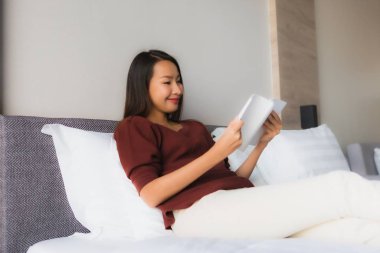 Yatakta kitap okuyan güzel Asyalı kadınların portresi.