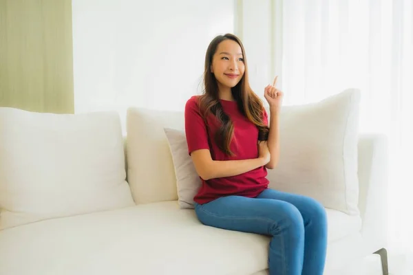 美丽动人的年轻亚洲女人幸福的微笑坐在沙发上 — 图库照片