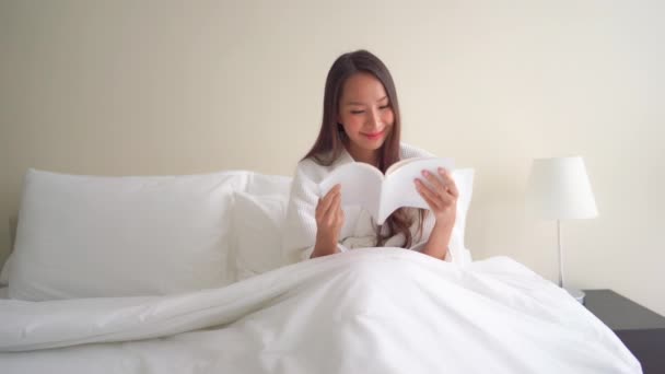 美しいアジアの女性が家で本を読んでいる映像 — ストック動画