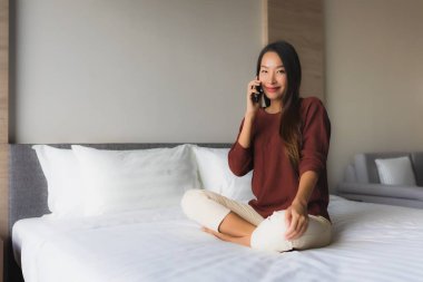 Yatakta cep telefonu kullanan güzel Asyalı kadınların portresi.
