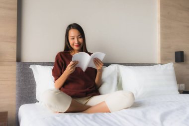 Yatakta kitap okuyan güzel Asyalı kadınların portresi.