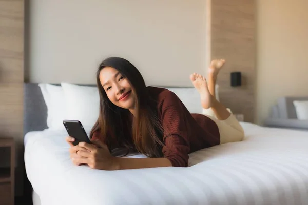 Porträt schöne junge asiatische Frauen mit Handy auf dem Bett — Stockfoto