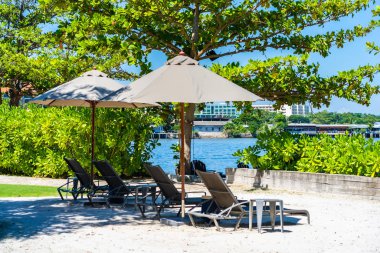 Şemsiye ve sandalye kumsalda ve denizde mavi gökyüzüyle