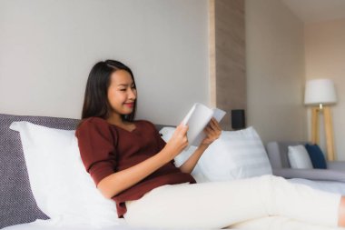 Yatakta kitap okuyan güzel Asyalı kadınların portresi.