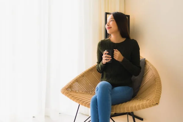 Porträtt vacker ung asiatisk kvinna hålla kaffekopp och sitter — Stockfoto