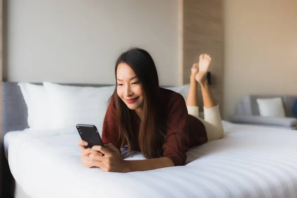 Портрет красивих молодих азіатських жінок, що використовують мобільний телефон на ліжку — стокове фото