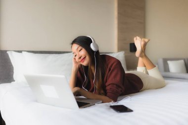 Bilgisayar ve kulaklık kullanan güzel Asyalı kadınların portresi.