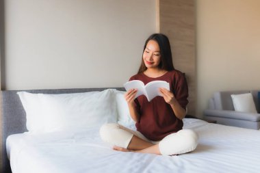 Yatakta kitap okuyan güzel Asyalı kadınların portresi.