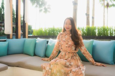 Güzel Asyalı genç kadınların portresi. Mutlu bir gülümseme. Kanepeye otur.