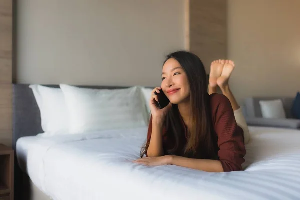Portré gyönyörű fiatal ázsiai nők mobiltelefon az ágyban — Stock Fotó