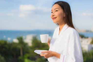 Güzel Asyalı genç kadınların portresi kahve fincanını elinde tutuyor.