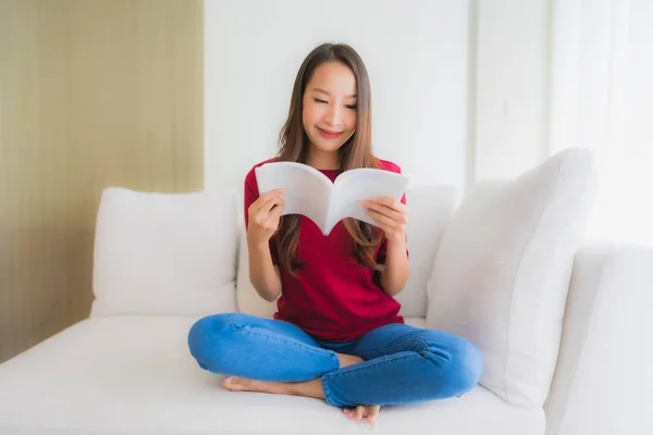 Portrét krásné mladé asijské ženy číst knihu na pohovce — Stock fotografie