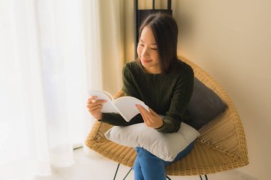 Asyalı güzel bir kadının kitap okuyup üzerine oturduğu portre.