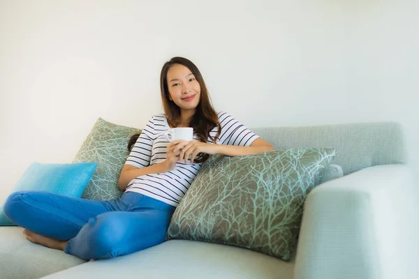 Portrait belle jeune femme asiatique sur canapé avec tasse de café — Photo